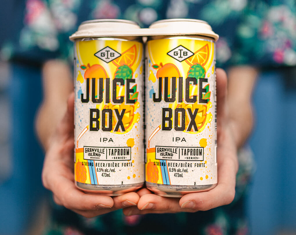 Man shares to camera 2 cans of Juice box GIB in focus the 2 cans