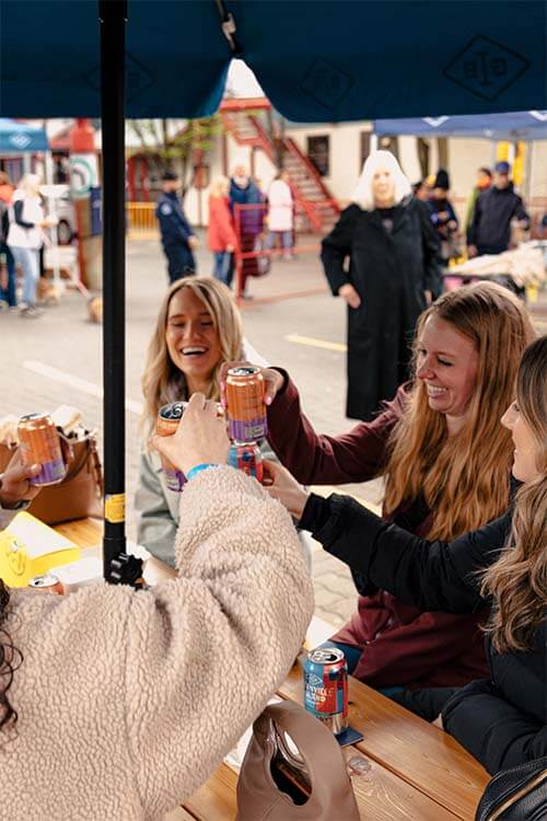 girls bumping cans smiling in a table