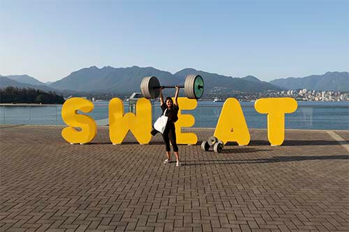 person carrying weight in front of word "sweat"