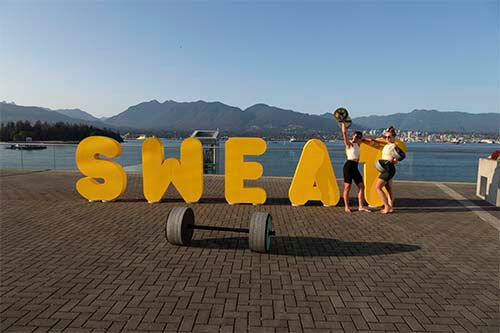 persons carrying weight in front of word "sweat"
