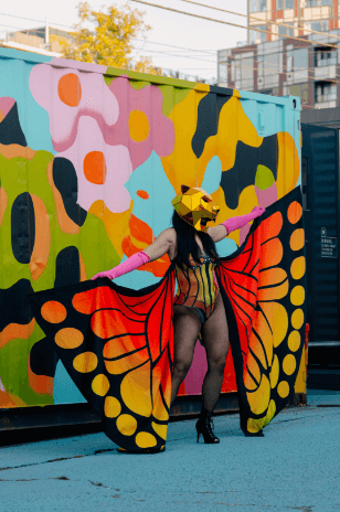 person posing in photo with butterfly costume and lion helmet