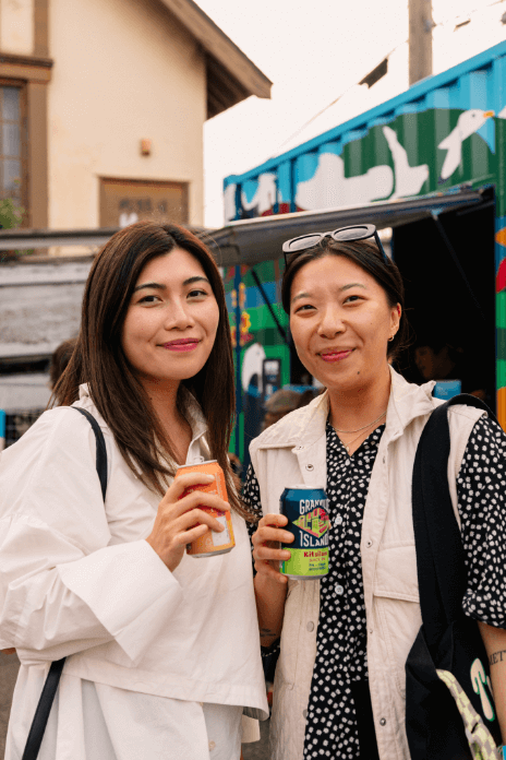 persons smiling and posing for photo with Granville cans in they hands