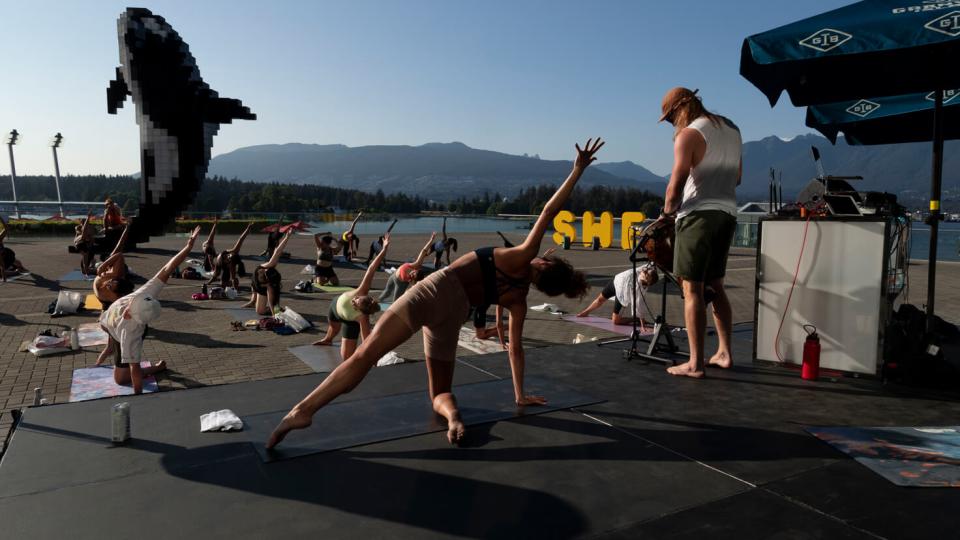 people on the beach on yoga position in event, with sea in the background